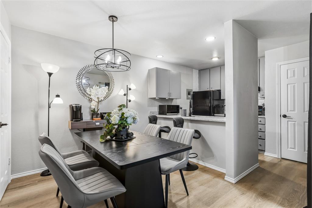 5540 Boca Raton Boulevard, Unit 181 Fort Worth, TX 76112 - Photo 10 of 21 Dining area featuring a contemporary chandelier, wood-finish flooring, and a breakfast bar with stone-finish countertops