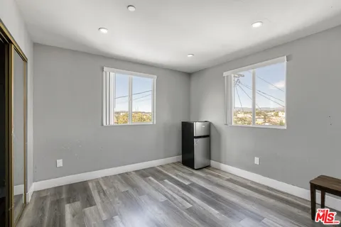 a view of empty room with wooden floor and fan