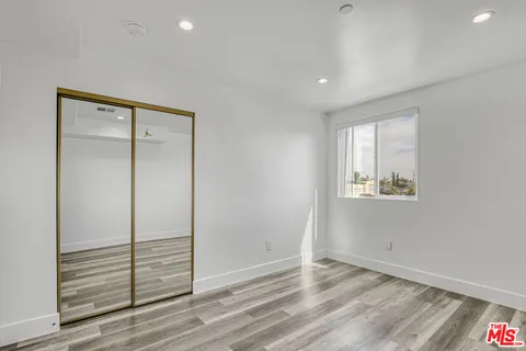 an empty room with wooden floor and mirror