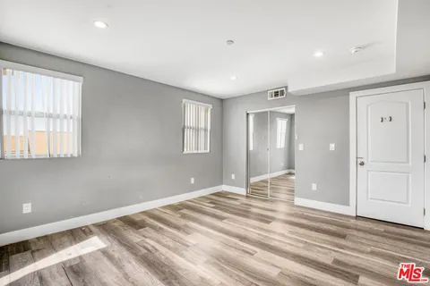 a view of empty room with wooden floor and fan