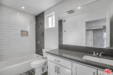 a bathroom with a granite countertop sink toilet mirror and bathtub