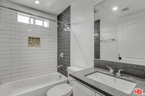 a bathroom with a granite countertop sink toilet and shower