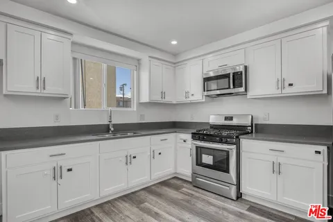 a kitchen with granite countertop white cabinets and stainless steel appliances