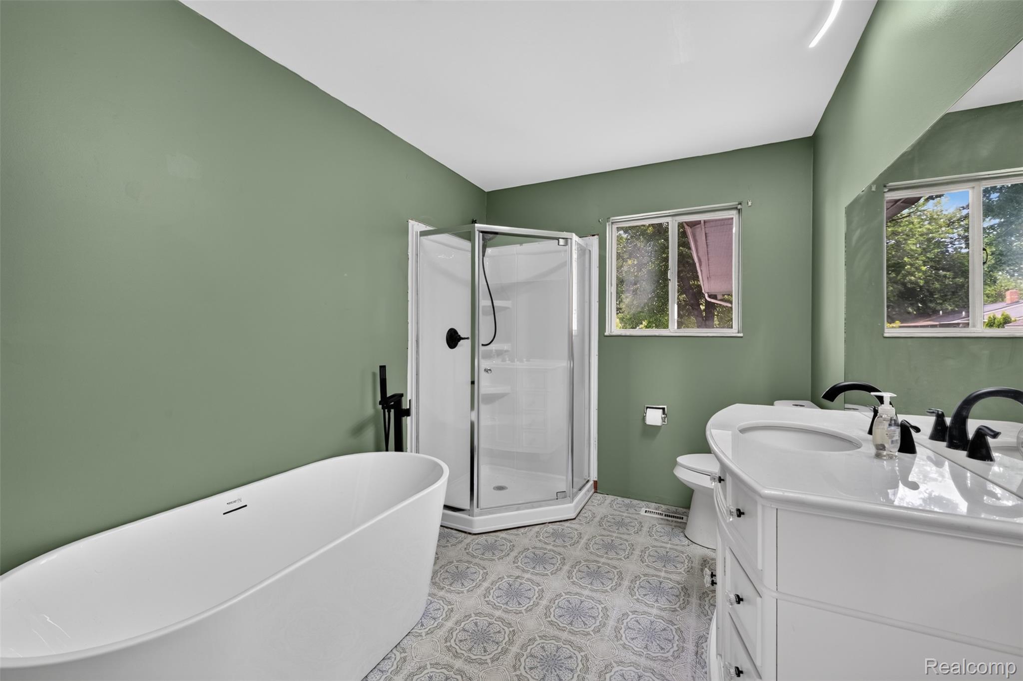 5457 Reid Road Swartz Creek, MI 48473 - Photo 24 of 51 Bright bathroom featuring a freestanding soaking tub, a corner shower enclosure, and a double vanity with undermount sinks