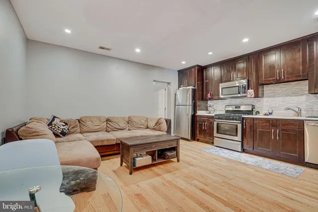 a living room with stainless steel appliances kitchen island granite countertop furniture and wooden floors