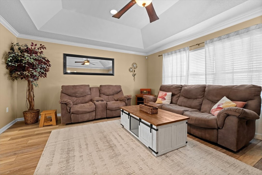 An elegant tray ceiling with crown molding elevates this inviting space lined with wood flooring.