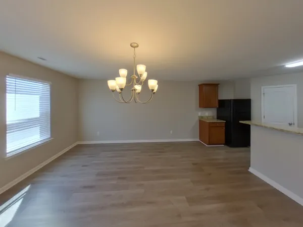 an empty room with chandelier fan and windows