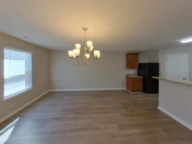 an empty room with chandelier fan and windows