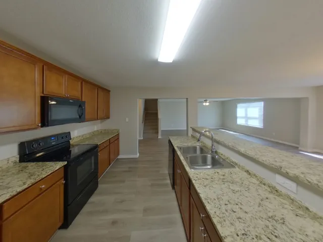 a kitchen with granite countertop a sink and wooden cabinets