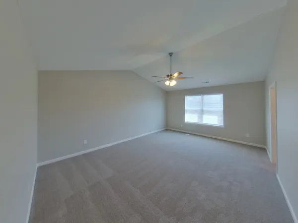 an empty room with a chandelier fan and windows