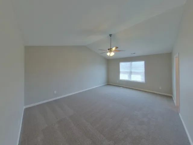 an empty room with a chandelier fan and windows