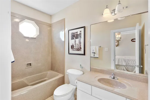 a bathroom with a granite countertop sink a toilet a mirror a vanity a bathtub and shower