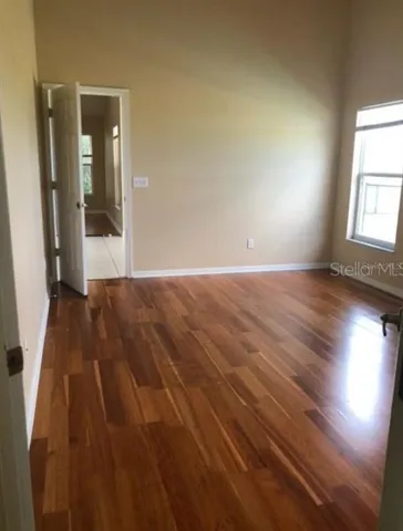 an empty room with wooden floor and windows