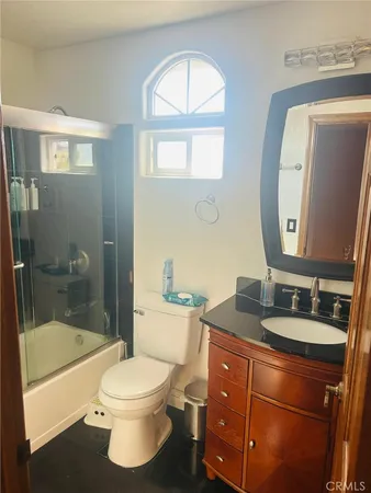 a bathroom with a bathtub shower sink vanity mirror and toilet