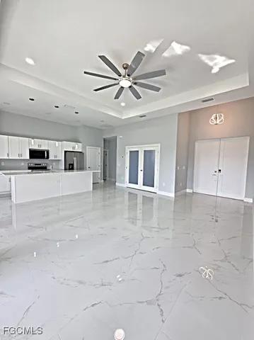 a view of a livingroom with a kitchen counter top space cabinets and a ceiling fan