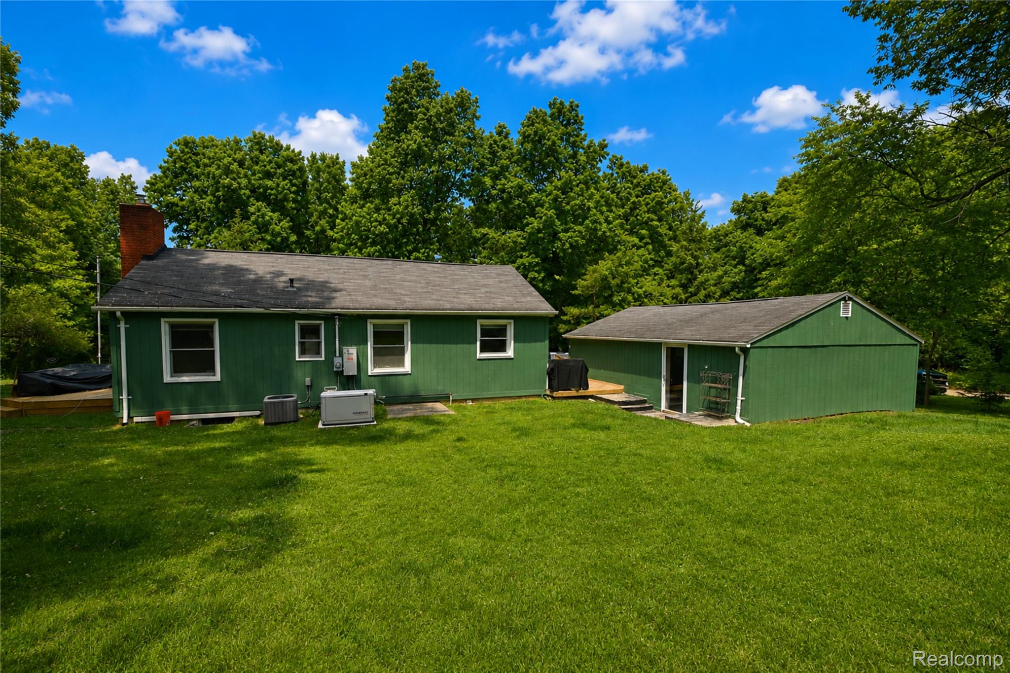 1405 Middle Road Highland, MI 48357 - Photo 2 of 18 Expansive rear yard featuring a detached auxiliary building and a wood deck