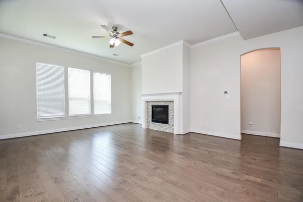 an empty room with wooden floor fireplace and windows