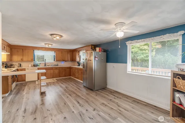 a kitchen with stainless steel appliances kitchen island hardwood floor sink stove and wooden cabinets