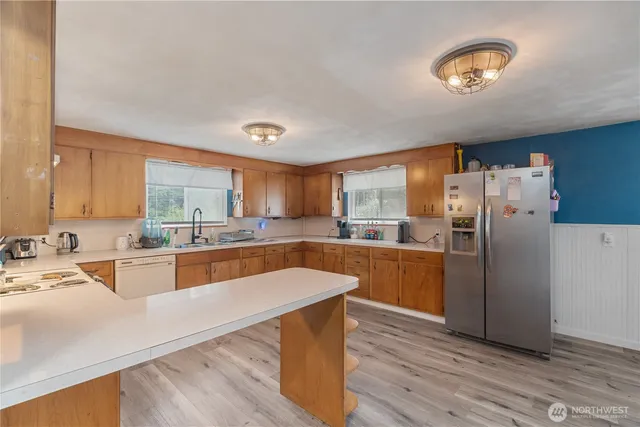 a large kitchen with a center island wooden floor and stainless steel appliances