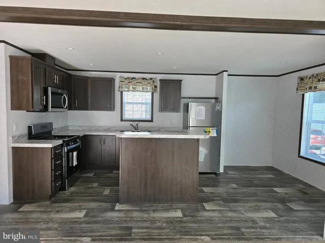 a kitchen with kitchen island granite countertop a sink cabinets and stainless steel appliances