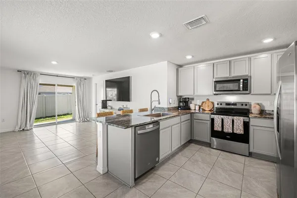 a kitchen with stainless steel appliances granite countertop a stove top oven a sink a counter top space and cabinets