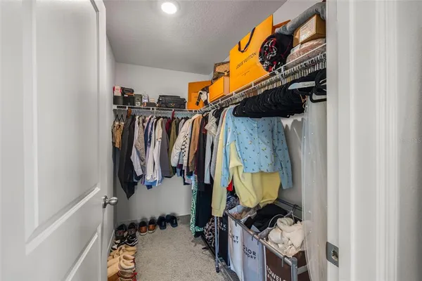 a view of walk in closet with clothes and shoes
