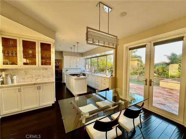 a open kitchen with stainless steel appliances granite countertop a stove a refrigerator a sink a dining table and chairs with wooden floor