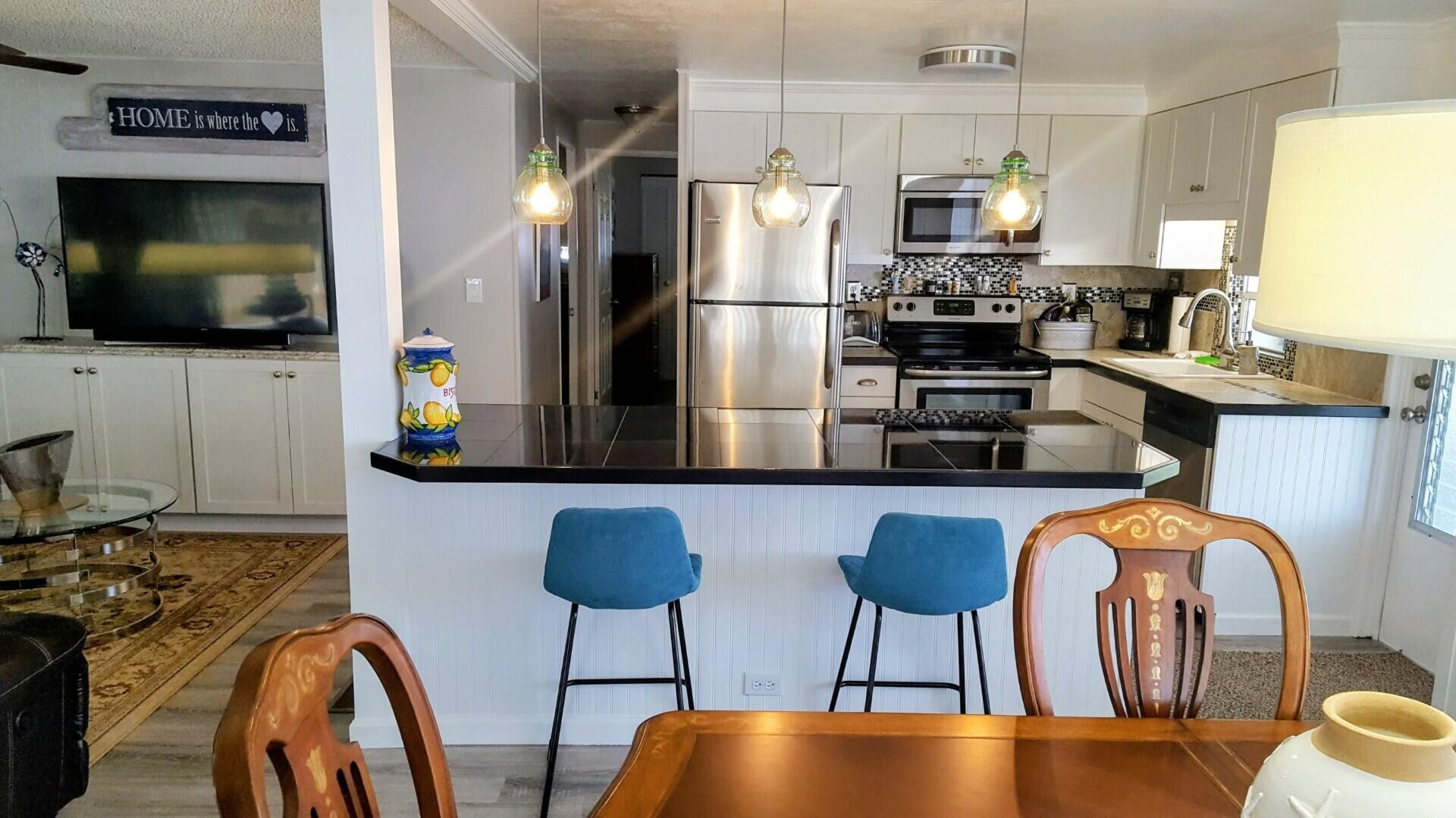 8281 South Street Boca Raton, FL 33433 - Photo 14 of 33 a kitchen with stainless steel appliances granite countertop a dining table chairs refrigerator and sink