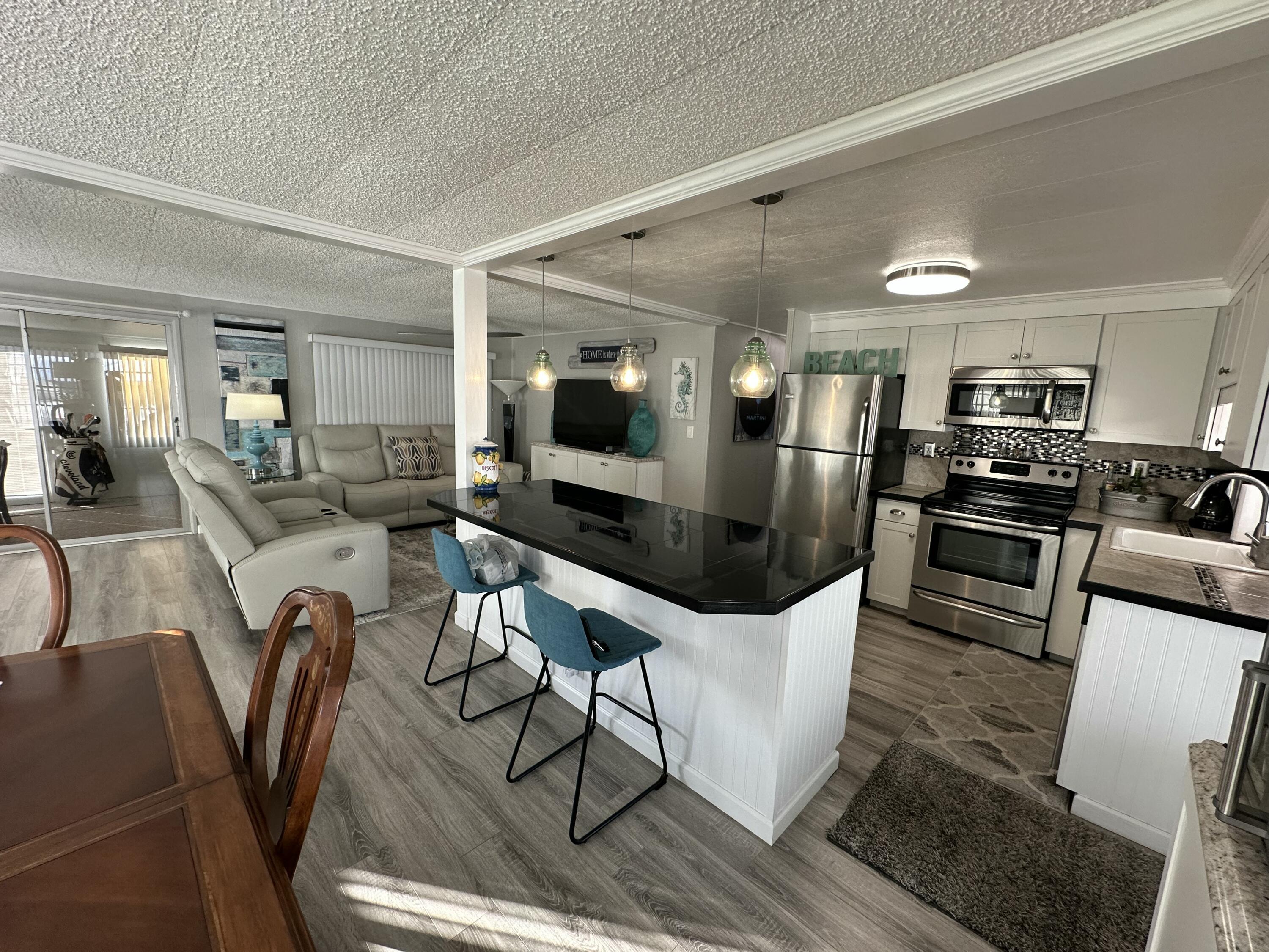 8281 South Street Boca Raton, FL 33433 - Photo 10 of 33 a kitchen with stainless steel appliances granite countertop a refrigerator a stove top oven a sink dishwasher and white cabinets with wooden floor