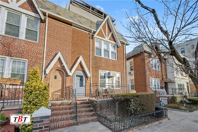 a view of a brick house with many windows and a tree