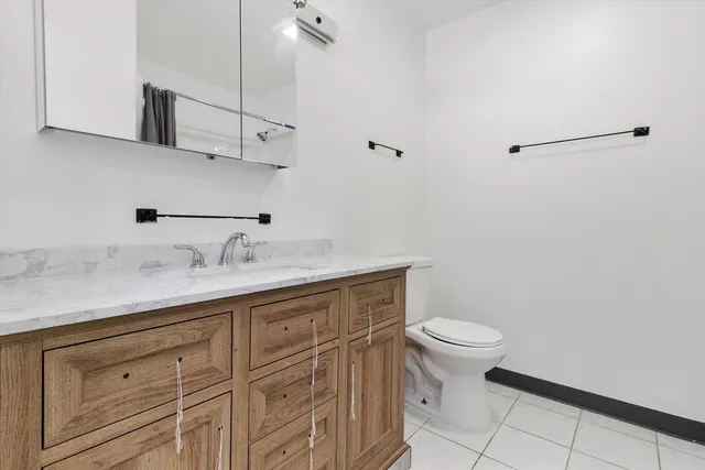 a bathroom with a granite countertop sink a toilet and mirror