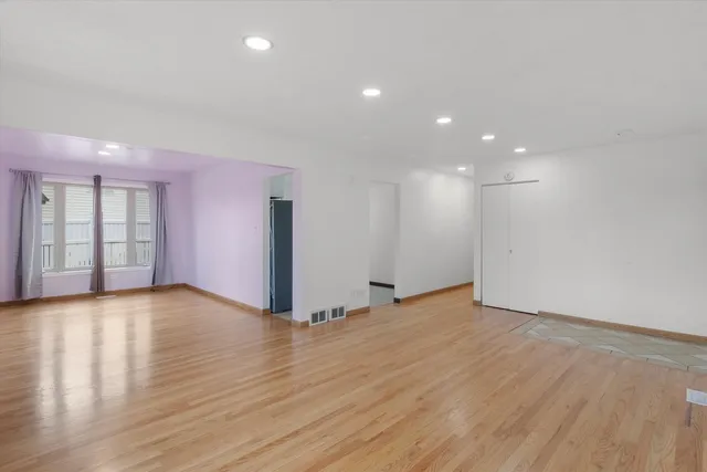 a view of an empty room with wooden floor and windows