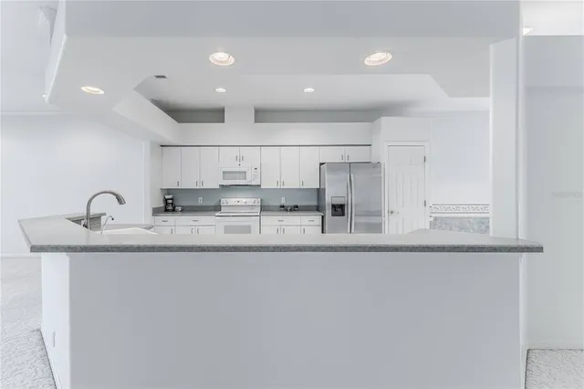 a open white kitchen with a sink and dishwasher with white cabinets