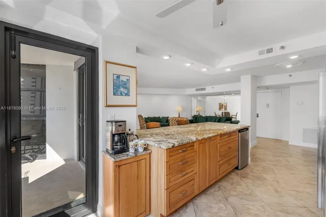 a large living room with stainless steel appliances kitchen island granite countertop a large window and white cabinets