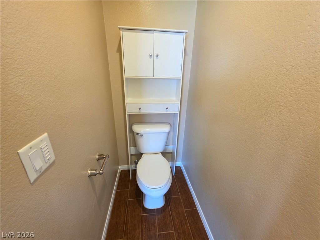 209 Opera House Street Henderson, NV 89012 - Photo 31 of 45 Rich wood plank tile floors complement textured neutral walls in this private powder room alcove.