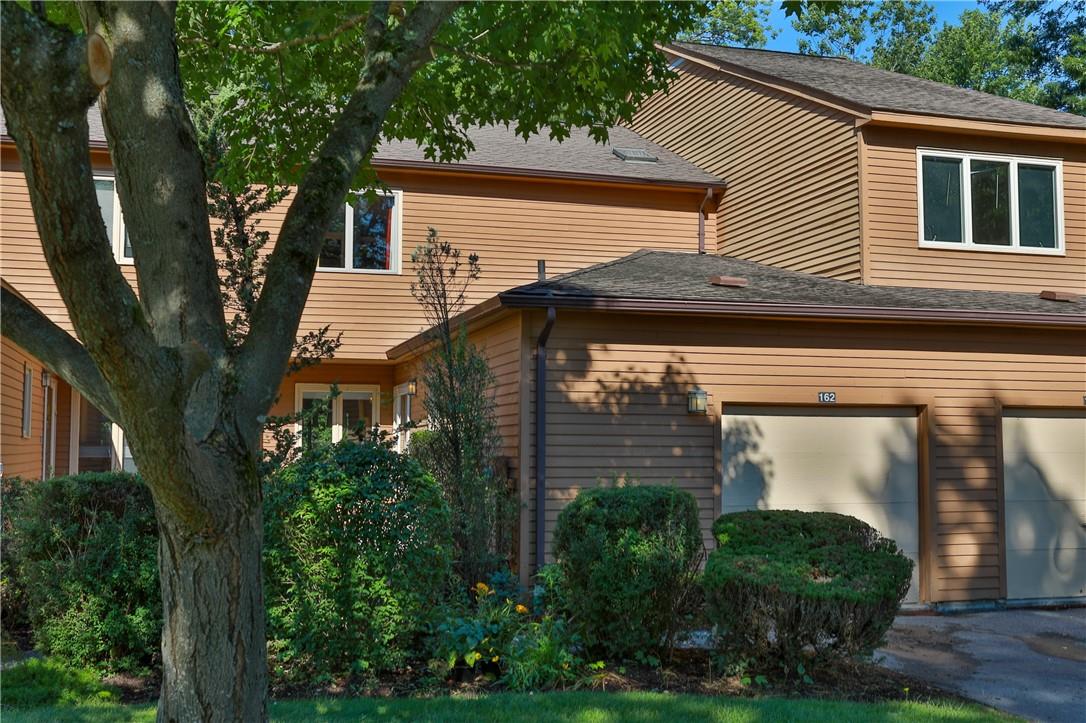 a view of a house with a small yard and a large tree