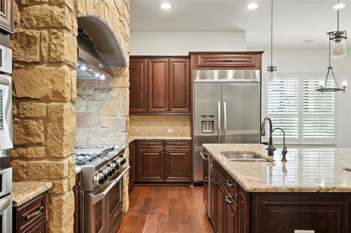 15729 De Fortuna Drive Bee Cave, TX 78738 - Photo 13 of 40 Kitchen featuring dark wood finished floors, high end appliances, tasteful backsplash, light stone countertops, and pendant lighting