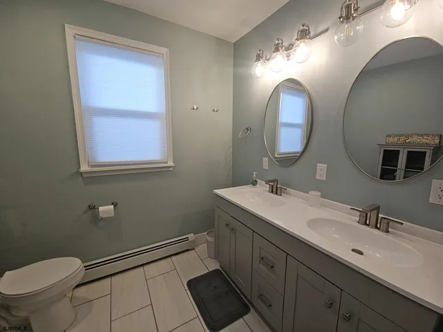 a bathroom with a double vanity sink mirror and toilet