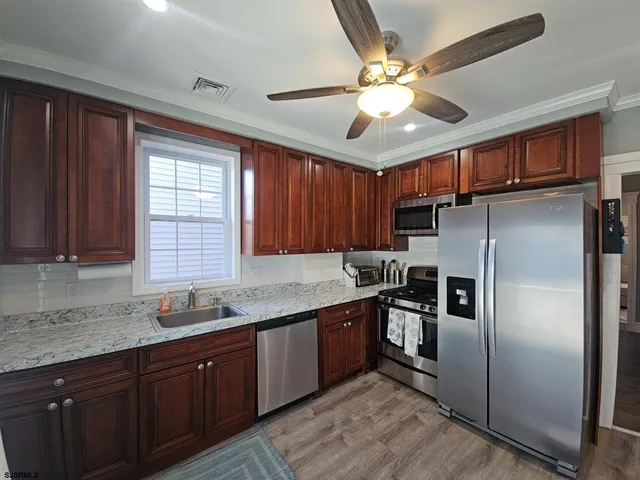 a kitchen with stainless steel appliances granite countertop a refrigerator a sink a stove and cabinets