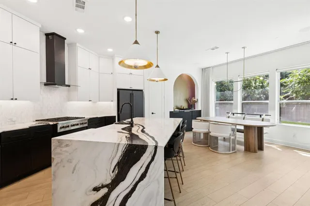 a kitchen with stainless steel appliances kitchen island granite countertop a stove a sink a dining table and chairs with wooden floor