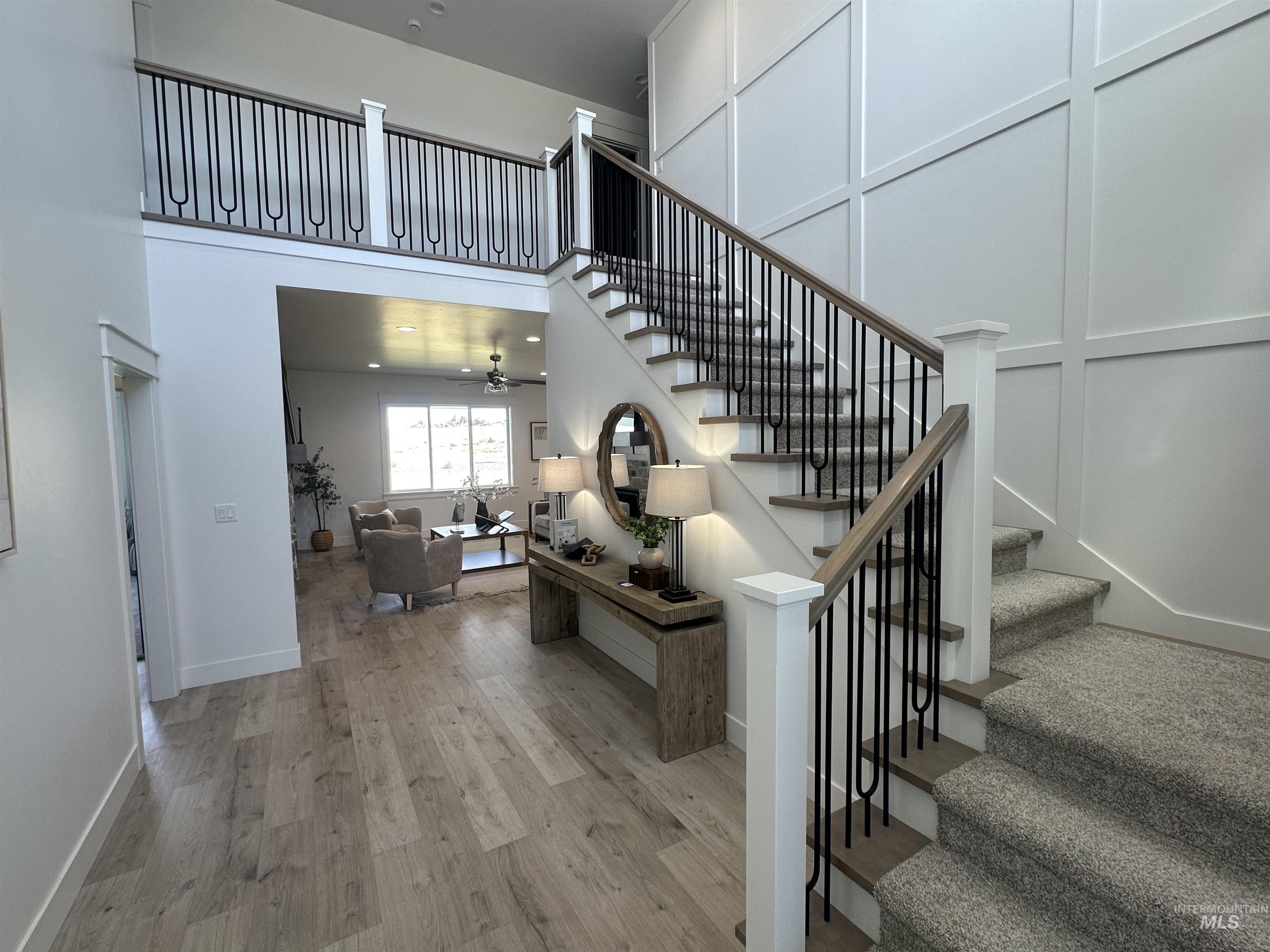 3035 Lake View Twin Falls, ID 83301 - Photo 15 of 41 Two-story entry foyer featuring wood-finish flooring, a grand staircase with carpeted treads and wrought iron balusters, a paneled accent wall, and an open balcony overlooking the space