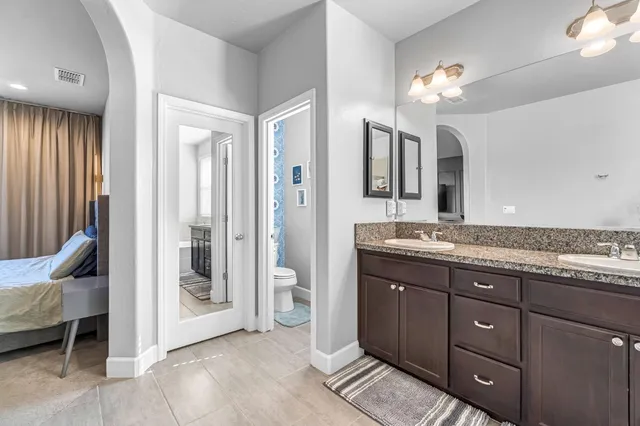 a bathroom with a granite countertop sink and a mirror with toilet