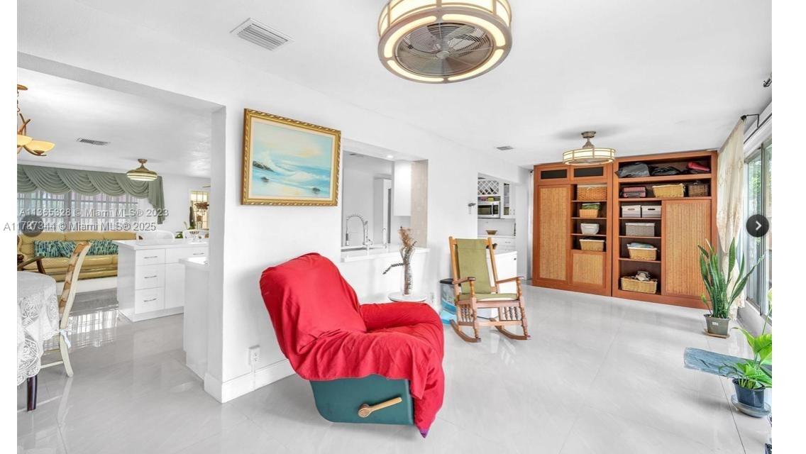 4941 Northwest 55th Court Tamarac, FL 33319 - Photo 28 of 30 a living room with furniture a dining table and a bookshelf