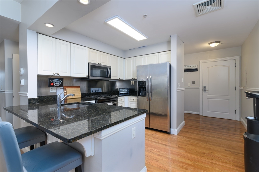 501 Commerce Drive, Unit 2310 Braintree, MA 02184 - Photo 2 of 23 a kitchen with a refrigerator a stove a sink and dishwasher with wooden floor