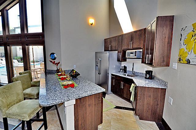 6910 Skillman Street, Unit 2016 Dallas, TX 75231 - Photo 16 of 23 a kitchen with stainless steel appliances granite countertop a stove a refrigerator a sink dishwasher and wooden cabinets with wooden floor