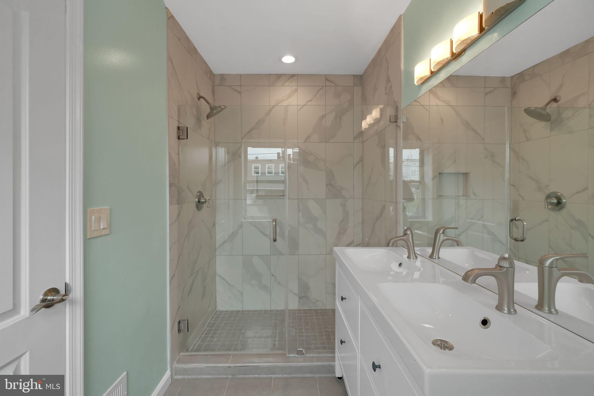 245 South Clinton Street Baltimore, MD 21224 - Photo 18 of 39 a bathroom with a shower sink and mirror