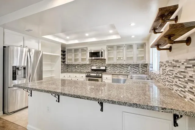 a kitchen with granite countertop a sink a counter top space cabinets stainless steel appliances and a counter top space