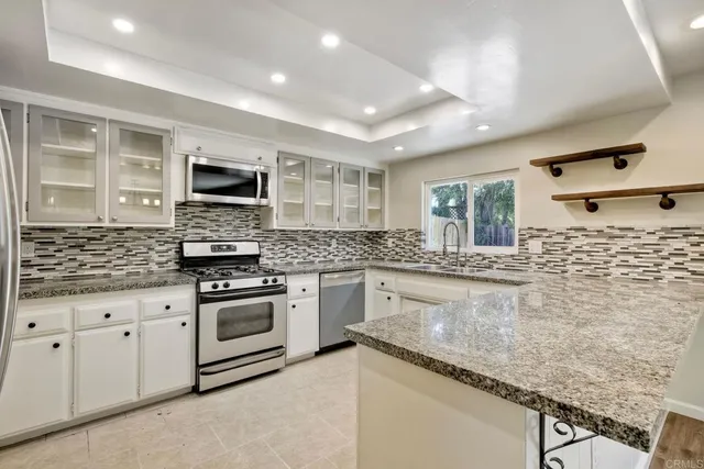 a kitchen with stainless steel appliances granite countertop a stove sink and cabinets