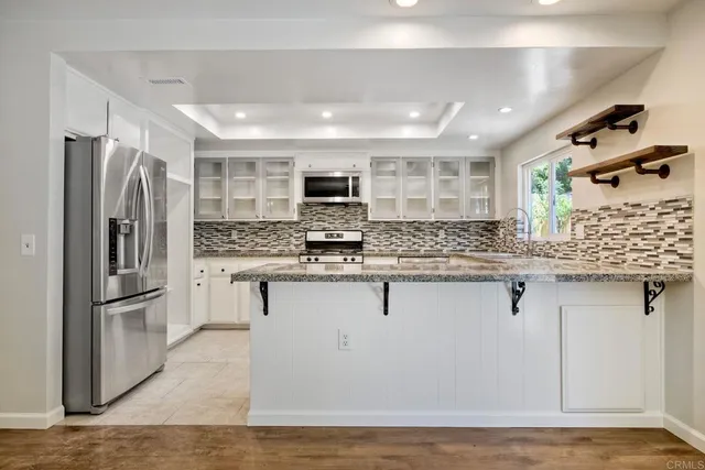 a kitchen with stainless steel appliances kitchen island granite countertop a refrigerator and a stove top oven
