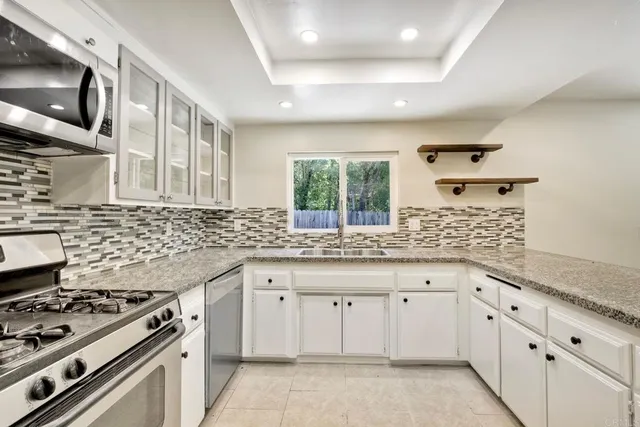 a kitchen with granite countertop a stove sink and cabinets